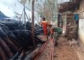 Petugas Pemadam Kebakaran Pacitan bersama anggota TNI melakukan proses penyemprotan dan pembasahan sisa-sisa kayu yang terbakar di kawasan pabrik UD Manfaat Berkah Grup, Desa Karangrejo, Kabupaten Pacitan, Senin (28/9/2026). (Foto: Istimewa)
