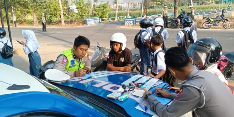 Petugas Satlantas Polres Pacitan saat mendata dan menilang sejumlah pengendara yang mayoritas pelajar dalam operasi penindakan pelanggaran di Jalan WR Supratman, Kelurahan Sidoharjo, Pacitan, Senin (5/10/2026). (Foto: Istimewa)