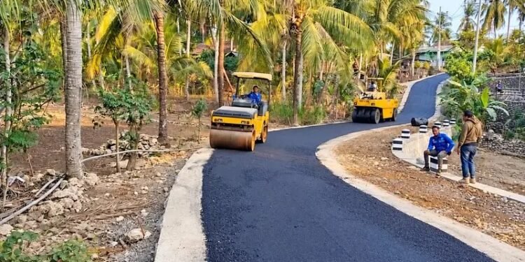 Pekerja dan alat berat menyelesaikan proses pengaspalan pada proyek peningkatan Jalan Sukoharjo–Buyutan sepanjang 2,74 kilometer di Kabupaten Pacitan, Jawa Timur. (Foto: Dok. Istimewa)