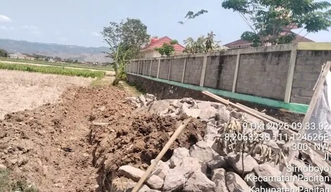 Tumpukan batu dan galian tanah pada lokasi pembangunan saluran air yang diduga tanpa papan informasi proyek di Desa Sirnoboyo, Kabupaten Pacitan, Rabu (14/10/2026). (Foto: Istimewa)