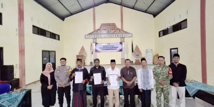 Babinsa, unsur kepolisian, perangkat desa, serta ketiga calon Kepala Desa berpose bersama usai penetapan di Gedung Pertemuan Desa Mangunharjo, Kecamatan Arjosari, Kabupaten Pacitan, Jumat (23/10/2026) malam. (Foto: Istimewa)